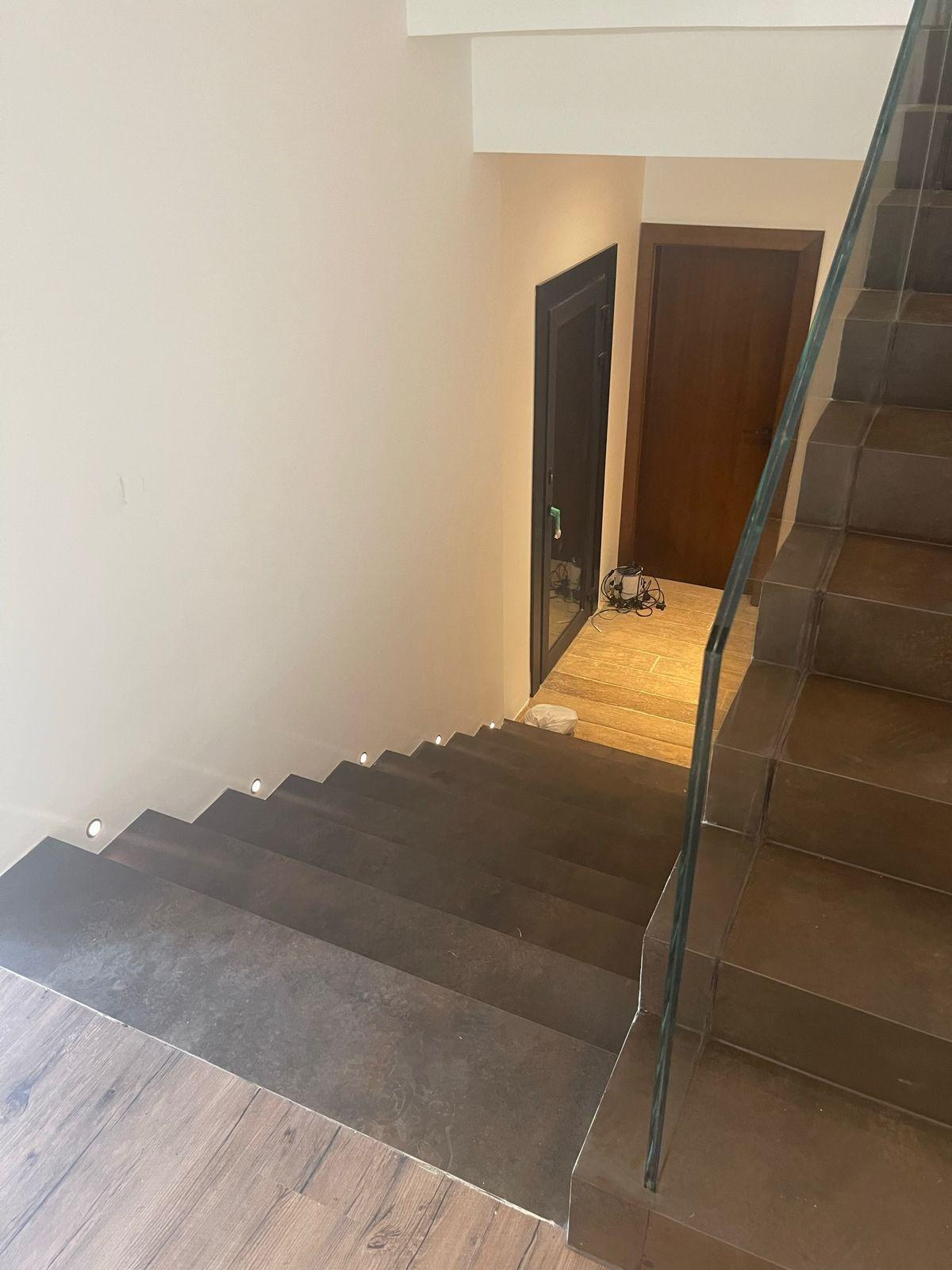 Escada escura em pedra com guarda-corpo de vidro