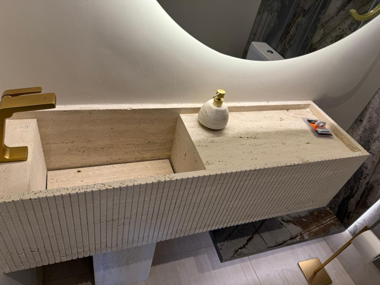 Lavabo em pedra clara com cuba esculpida e acabamento canelado
